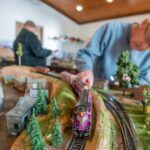 An elderly man looking at life size mock up of a town with a train and train tracks