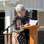 A woman speaking outside of twin lakes community building