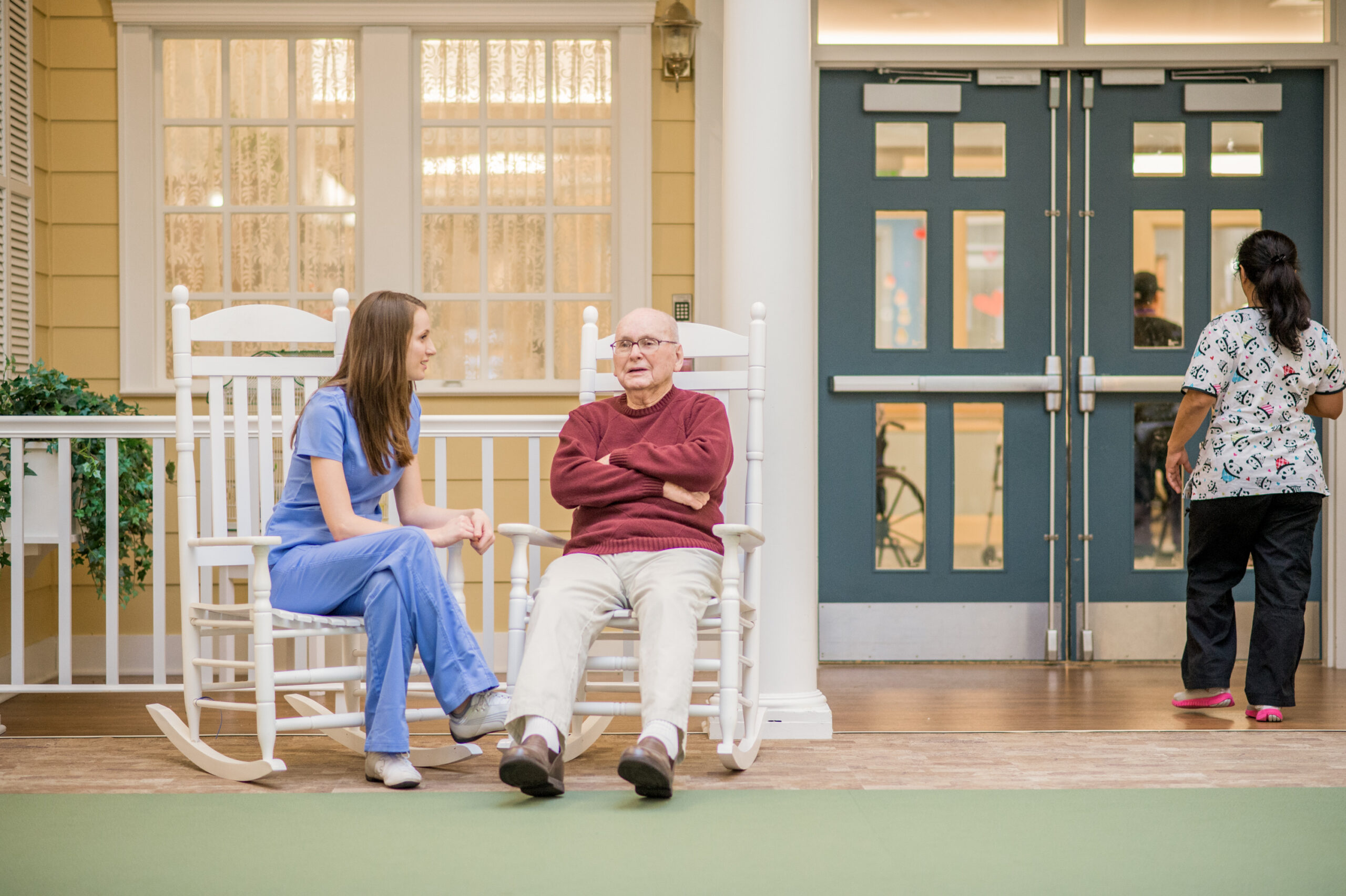 A nurse and an elderly man sitting in two rocking chairs